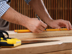 Handwerker misst und markiert Holzbauteil präzise für den Ausmessservice von SponHolz