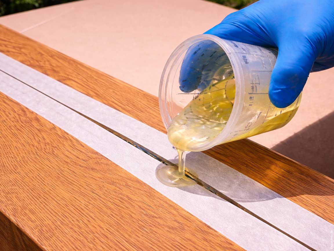 Epoxi-Reparatur eines Risses in einer massiven Eichenplatte mit Epoxidharz im Querformat