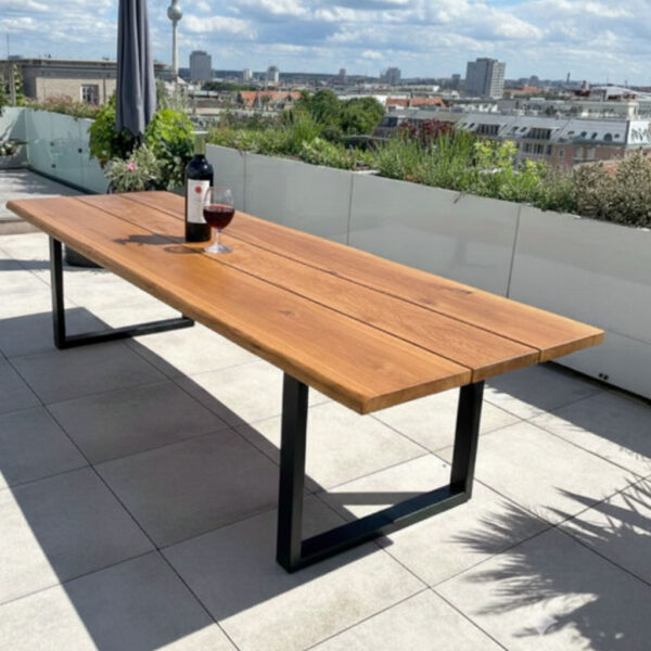 Klappbarer Gartentisch aus 4 cm massiver Eiche mit schwarzem Stahlgestell auf moderner Dachterrasse mit Berliner Skyline im Hintergrund