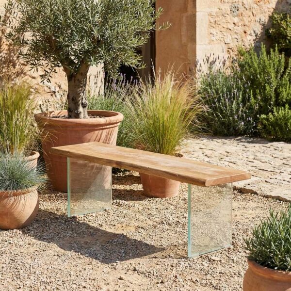 Holzbank mit Glasgestell auf Kies-Terrasse im mediterranen Stil mit Olivenbaum